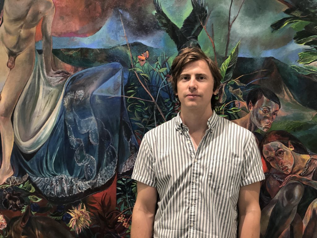 Louis Watts in front of current exhibit by Jennifer Meanly