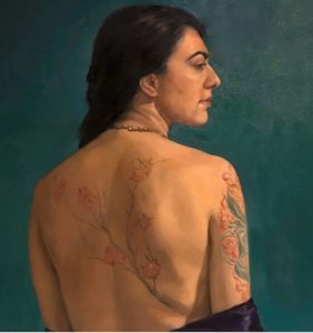 image of dark haired woman, back facing view, neck shoulders and back bearing a tattoo of pink blossoms