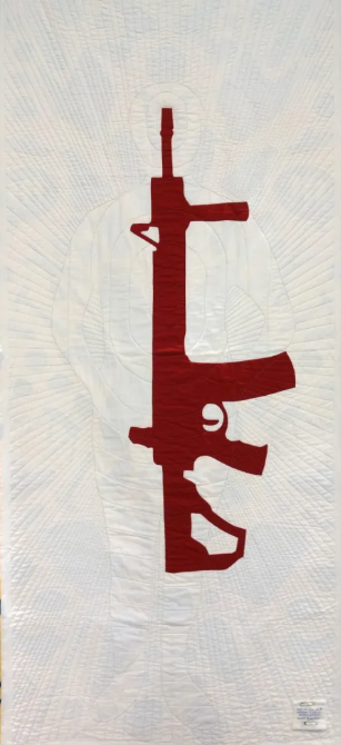 Reverse side of Robinson's quilt featuring the outline of a human on white material overlaid by an automatic weapon in red