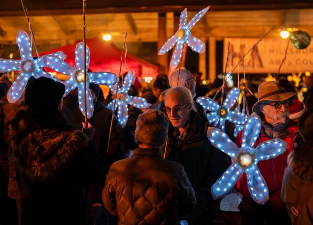 crowd of people holding light-up flower wands