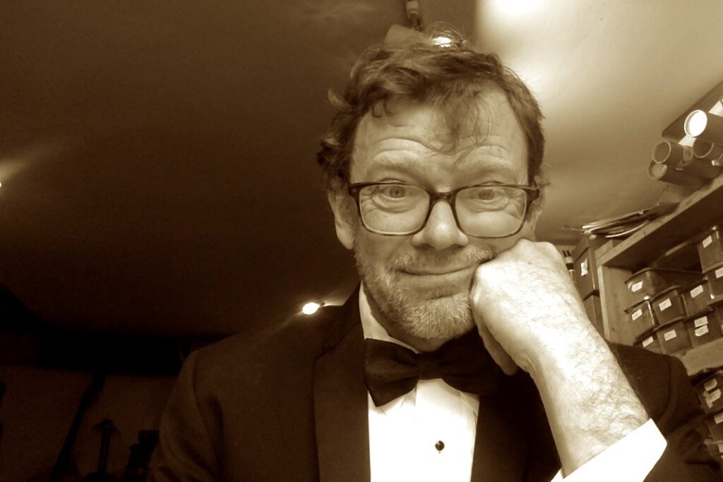 Greg Bell posing in a tuxedo