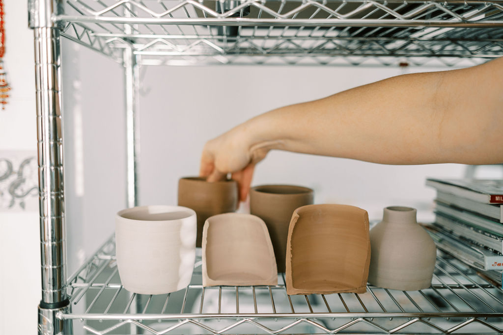 someone placing a clay pot on a metal rack